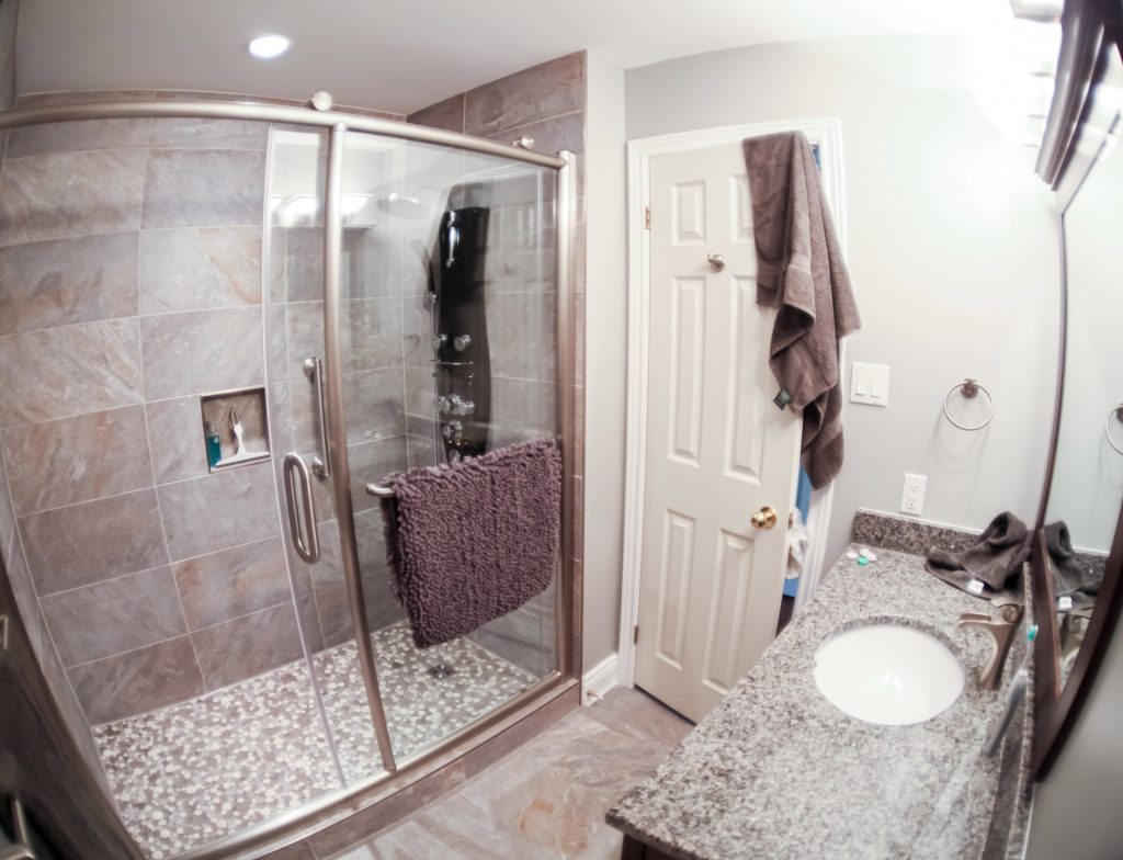 Tiled shower with curved glass enclosure beside a bathroom vanity