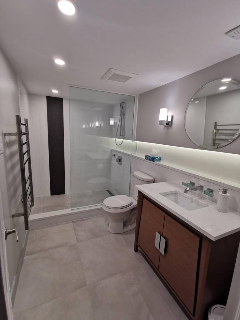 Bathroom remodel with wooden vanity and backlit accent wall