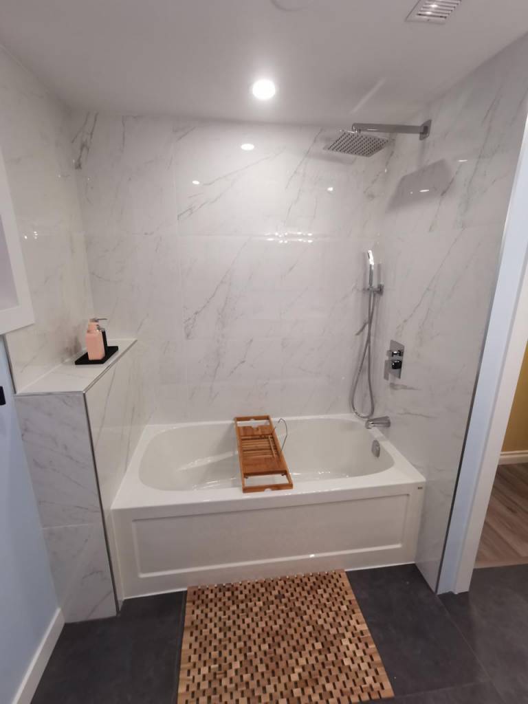 white bathroom renovation with bathtub wall panels and chrome shower fixtures
